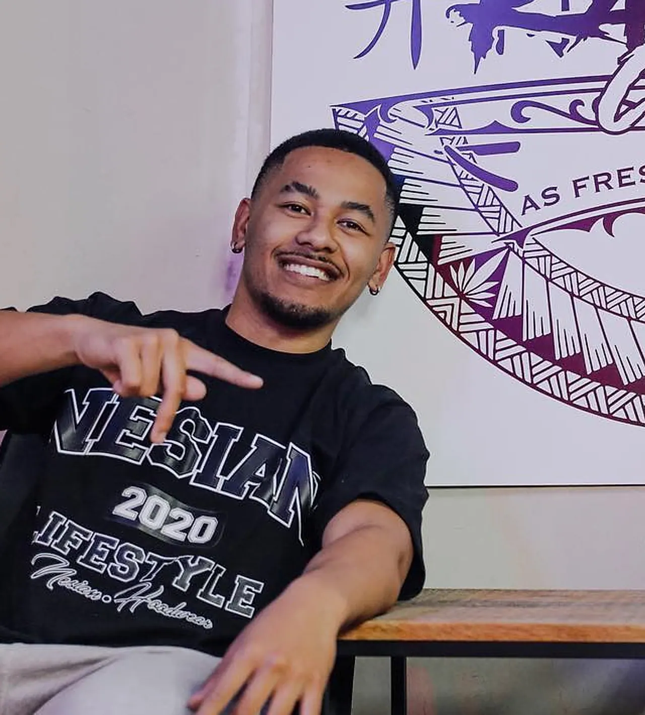 Kawza in the studio, seated in front of the Kawzacutz mural painted on the wall.