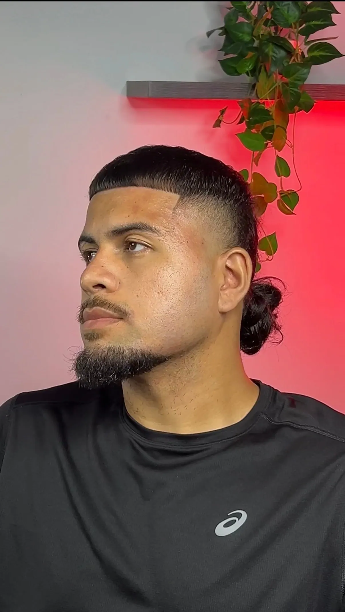 Straight-edged fringe over a high skin fade, with the length tied back into a bun.